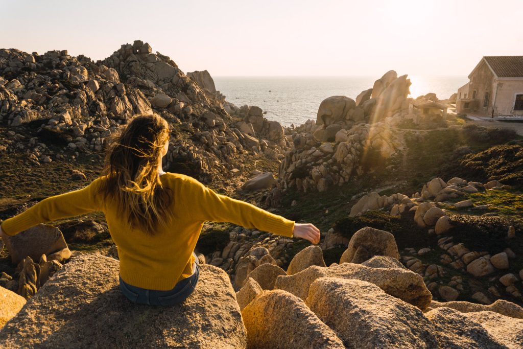 Chica mirando atardecer junto al mar